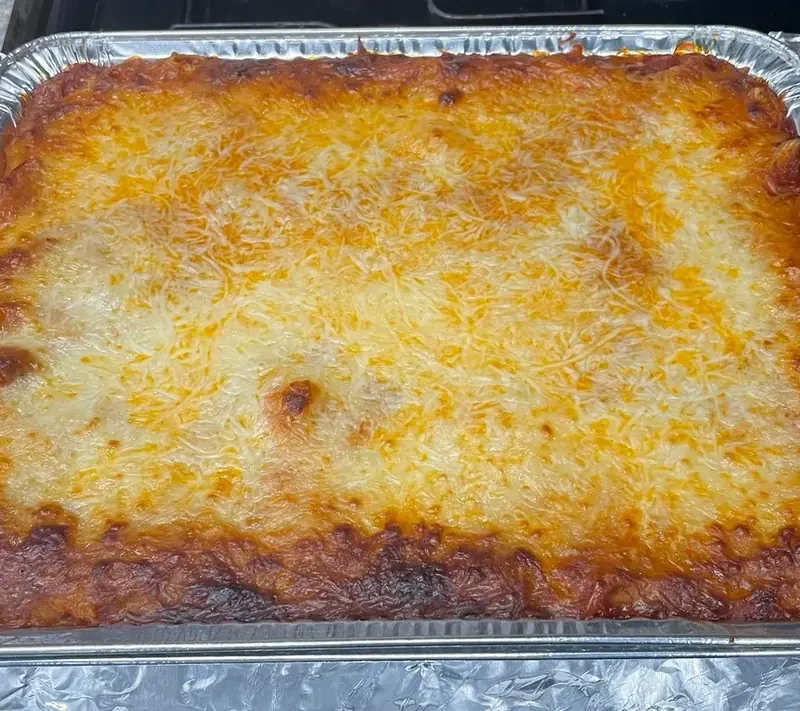 Baked Ziti with Red Sauce with a golden, bubbly melted cheese top in a foil pan