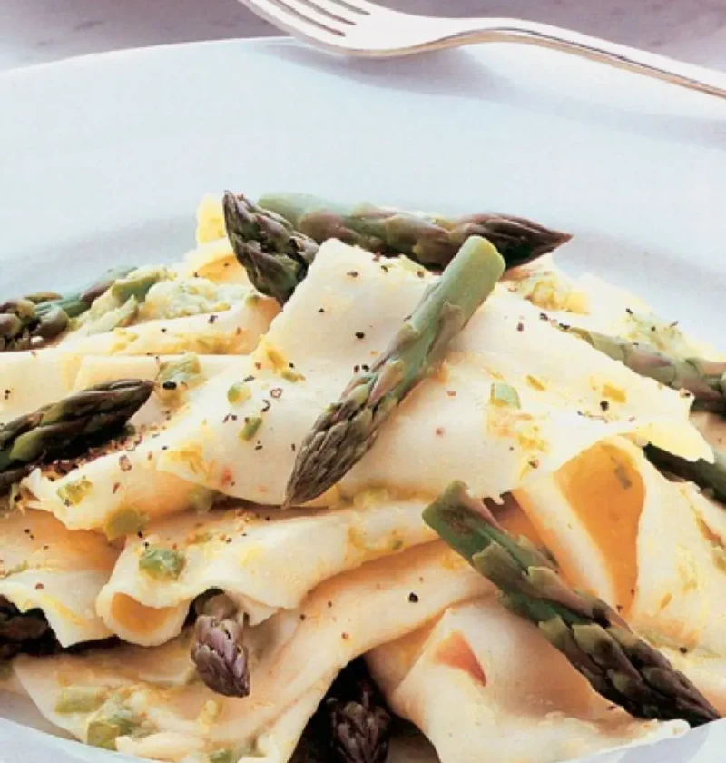 Brandelli with asparagus sauce: torn fresh pasta pieces topped with whole asparagus tips on a white plate