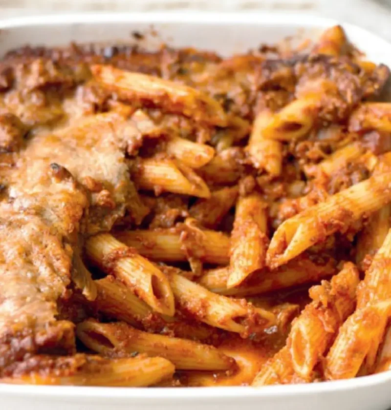 Easy baked pasta in a white baking dish, penne in a tomato sauce with a browned cheese top