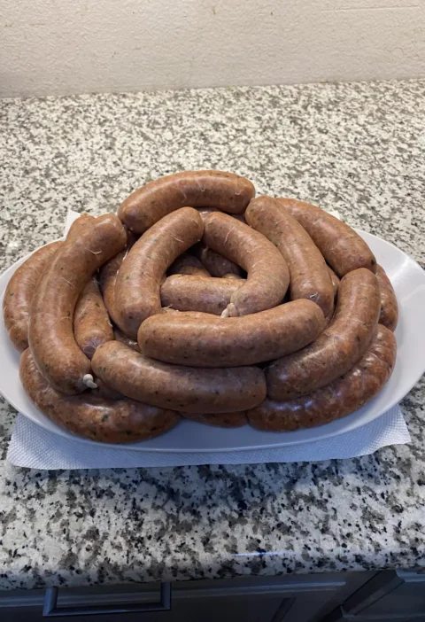Easy Italian hot sausages recipe: coiled links of homemade sausage piled on a white platter