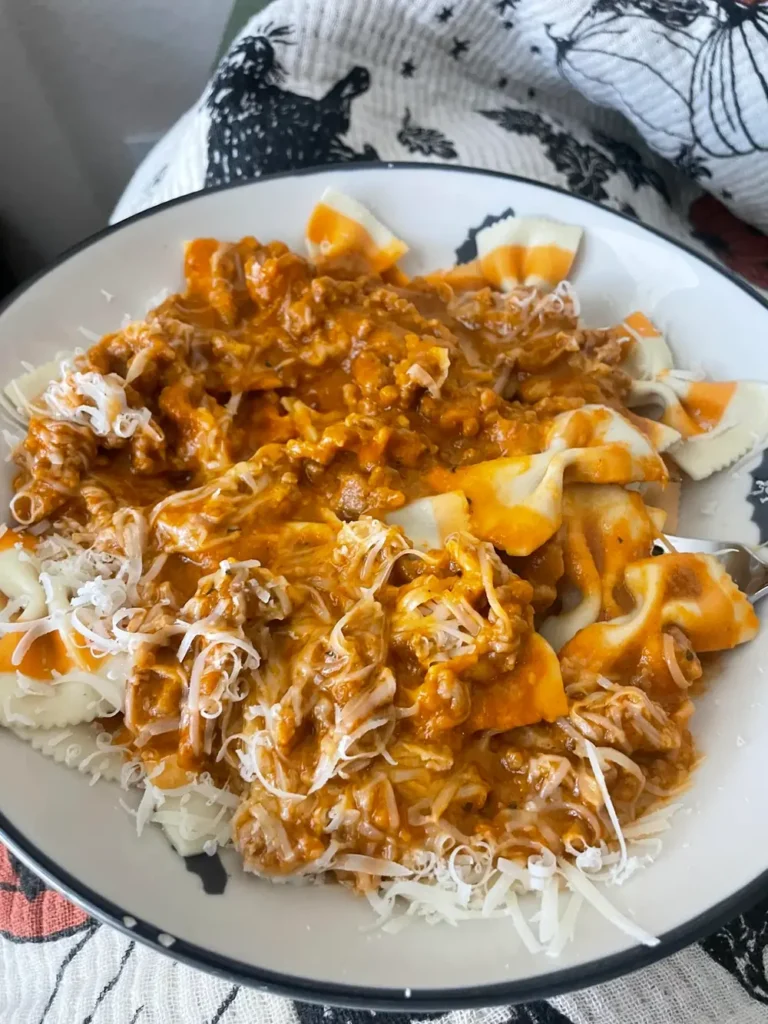 Plate of bow tie pasta with creamy Italian sausage pumpkin sauce and shredded cheese on top