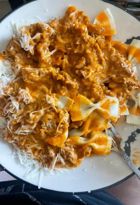 Easy Italian sausage pumpkin sauce over orange and white bow tie pasta with grated Parmesan on a plate