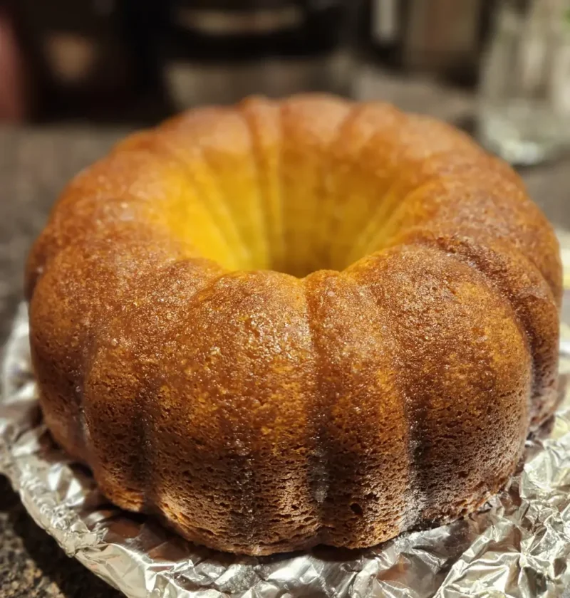 Easy olive oil pumpkin bundt cake with a golden brown crust sitting on foil