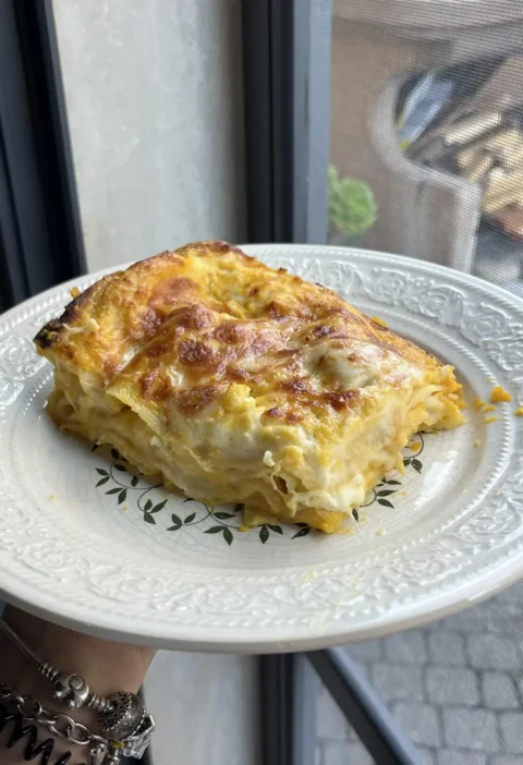 A square slice of easy pumpkin lasagna with golden layers and browned cheese on a white plate