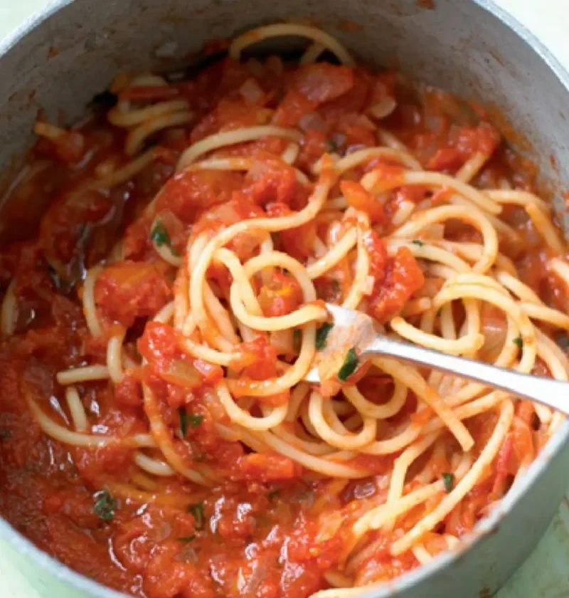 Easy tomato sauce with spaghetti in a saucepan, a fork lifting the pasta
