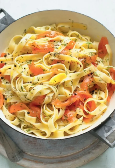 Fettuccine with smoked salmon in a white pan with dill and black pepper