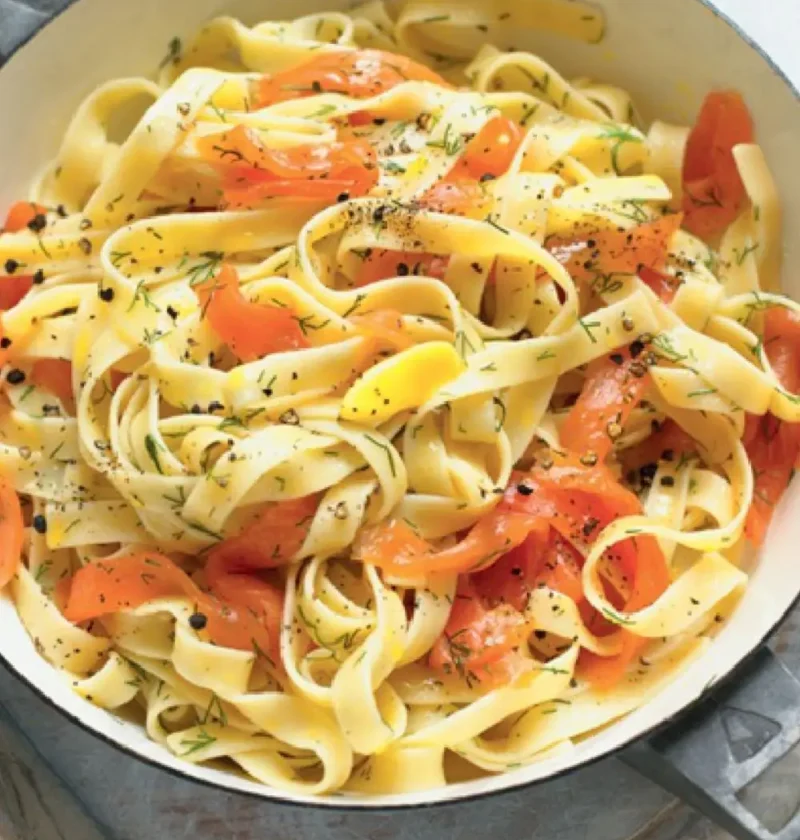 Fettuccine with smoked salmon in a white pan with dill and black pepper