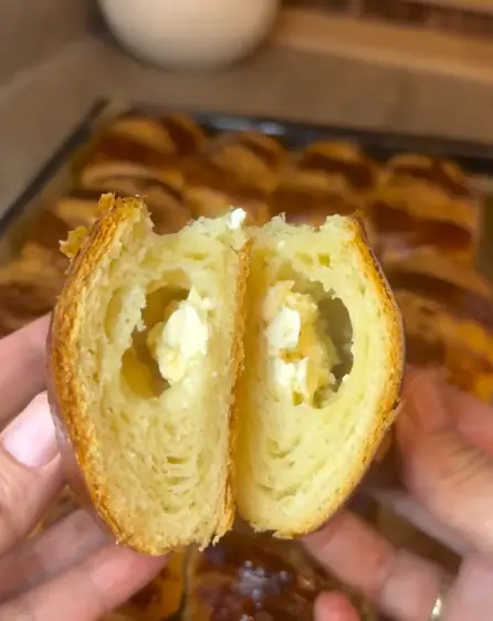 A layered pastry roll torn open to show flaky crumb and feta filling inside