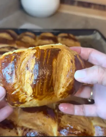 A golden layered pastry roll with glossy egg wash and deep slits across the top