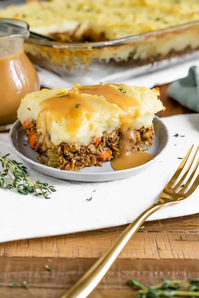 Gravy poured over a slice of lentil shepherd's pie on a gray plate