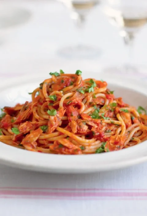 Linguine with tuna fish sauce in a white bowl, topped with chopped parsley