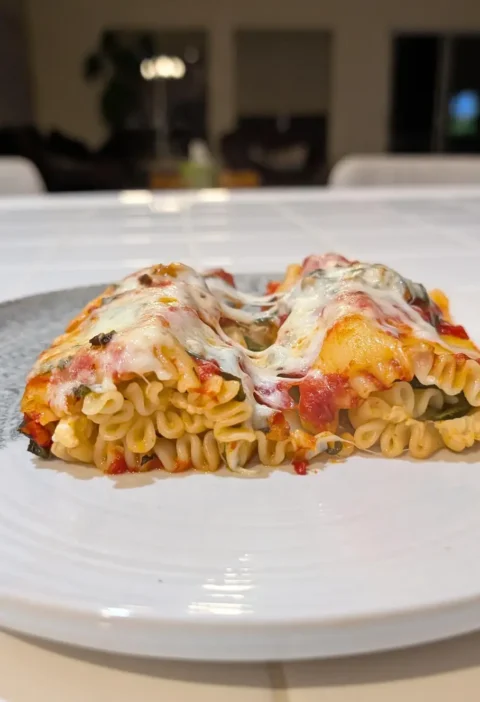 Mummy lasagna rolls on a white plate topped with marinara and melted cheese