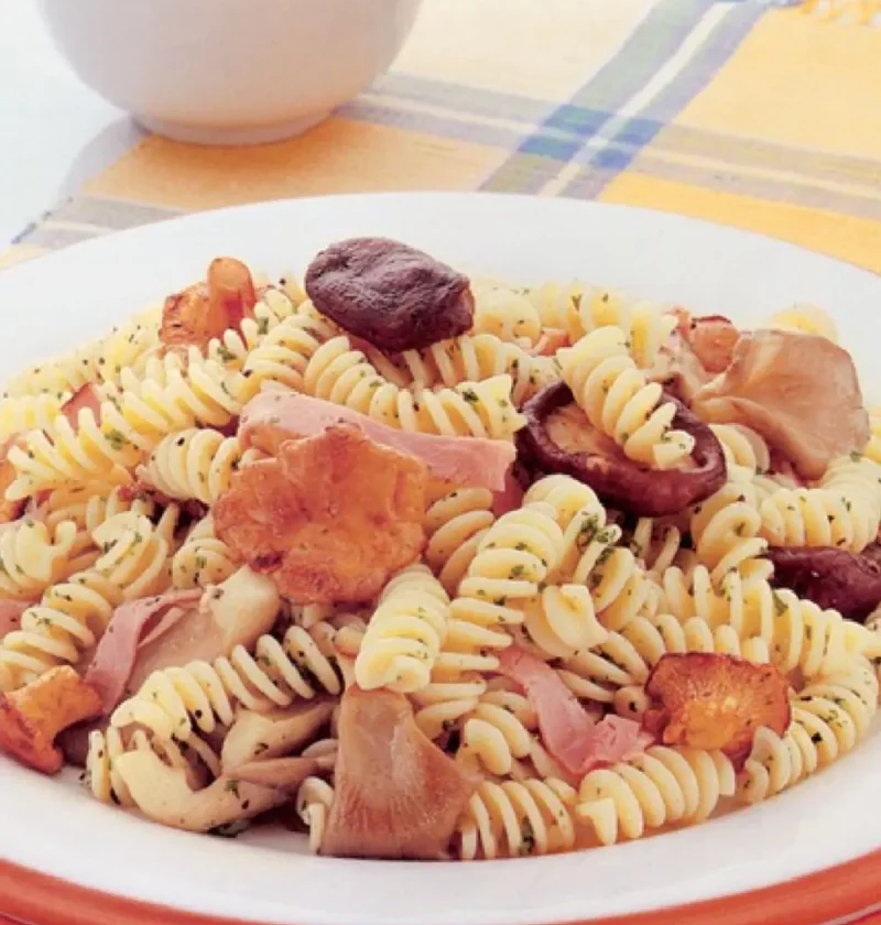 Pasta for All Seasons: fusilli with shiitake, oyster and chanterelle mushrooms and smoked ham on a white plate
