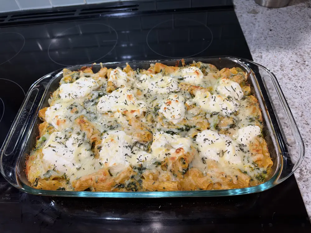 Pumpkin baked mac and cheese in a glass baking dish, golden and bubbly with dollops of ricotta on top