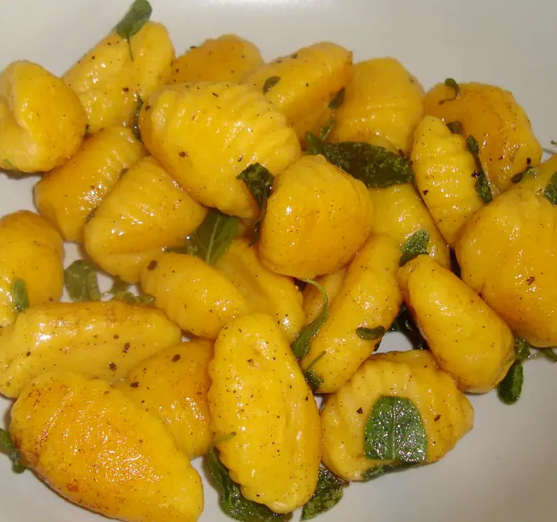 Pumpkin gnocchi with sage butter and fresh sage leaves on a white plate