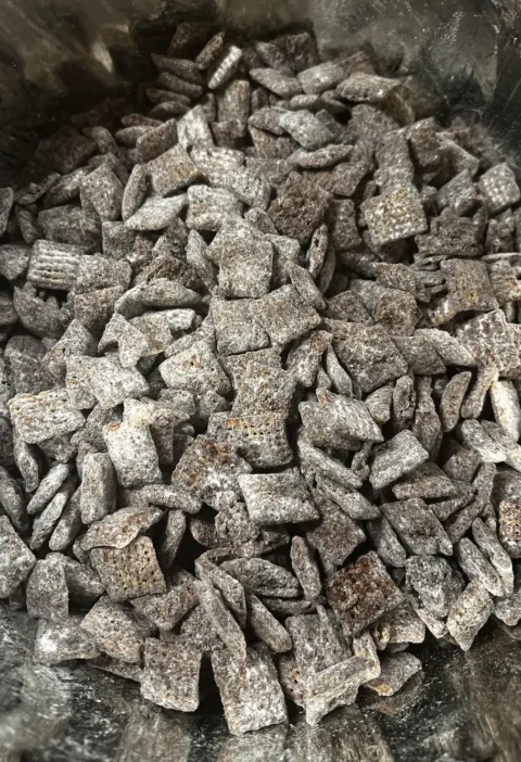 Pumpkin spice puppy chow, rice Chex cereal coated in chocolate and powdered sugar, piled in a bowl