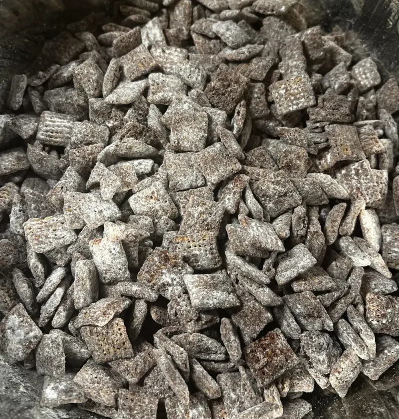 Pumpkin spice puppy chow, rice Chex cereal coated in chocolate and powdered sugar, piled in a bowl