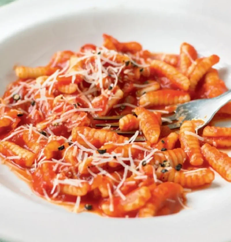 Sardinian gnocchi with tomato sauce in a white bowl, topped with grated pecorino and basil