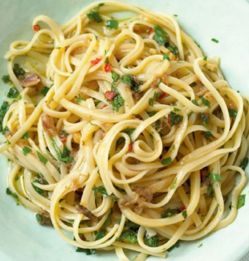 A pale green bowl of sparrow tongues with anchovies, flat pasta tossed with chopped parsley and red chili