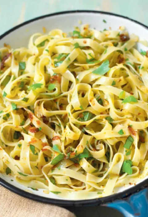 Tagliatelle with bottarga, chopped parsley and basil in a white enamel skillet