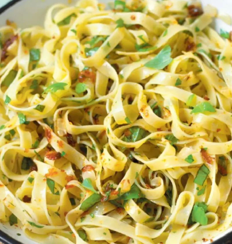 Tagliatelle with bottarga, chopped parsley and basil in a white enamel skillet