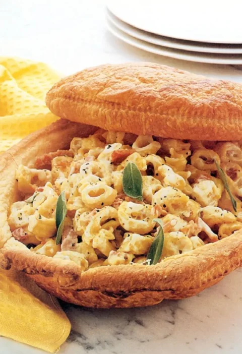 Tortellini in puff pastry shell with ham and sage leaves, lid propped open