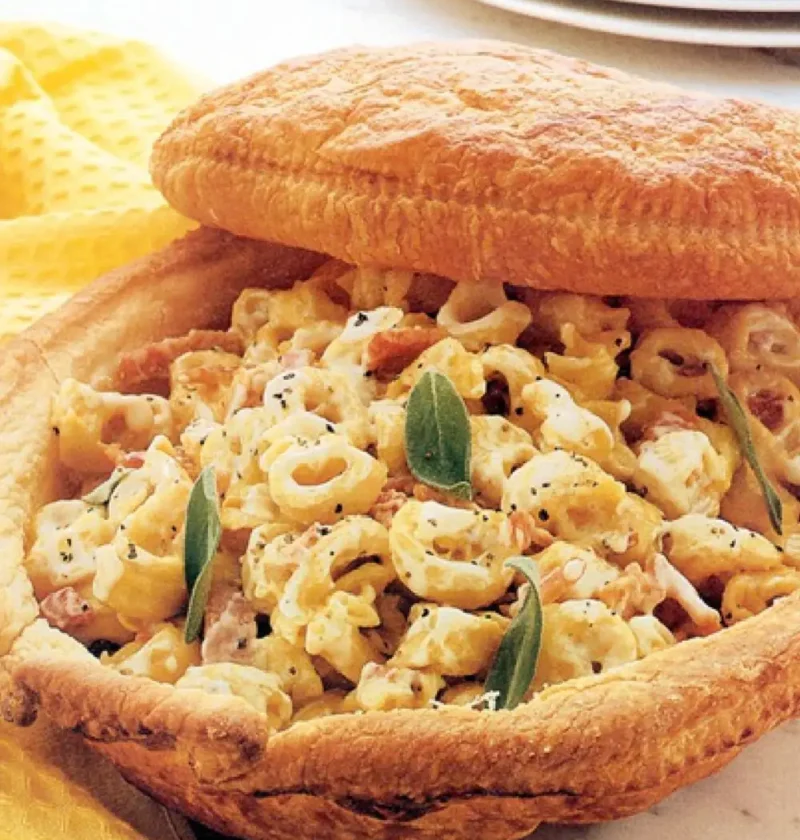 Tortellini in puff pastry shell with ham and sage leaves, lid propped open